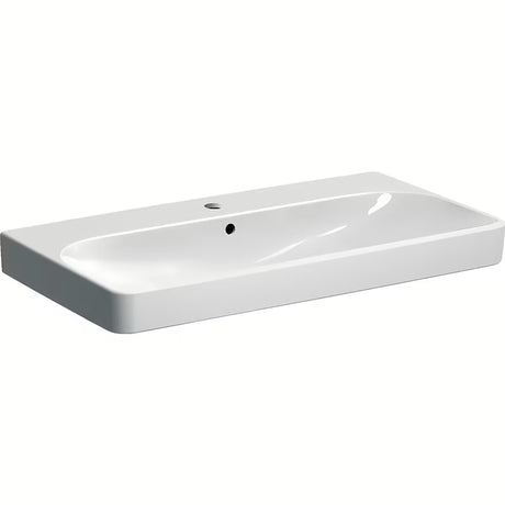 Baltas pakabinamas praustuvas Geberit Smyle Square 90x48 cm iš sanitarinės keramikos, su persipylimu ir anga pro maišytuvui.