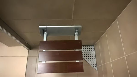 Atlenkiamos dušo sėdynė Multi rudos spalvos, iš masyvios Bulletwood medienos, su sieniniu laikikliu.